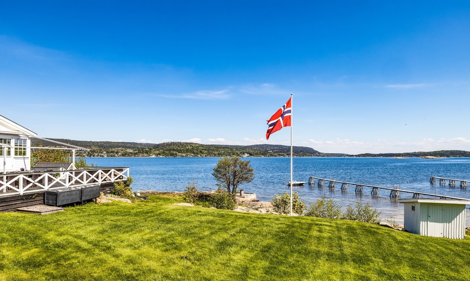 Pent opparbeidet tomt med stor gårdsplass, gressplen og beplantninger. Galleribilde