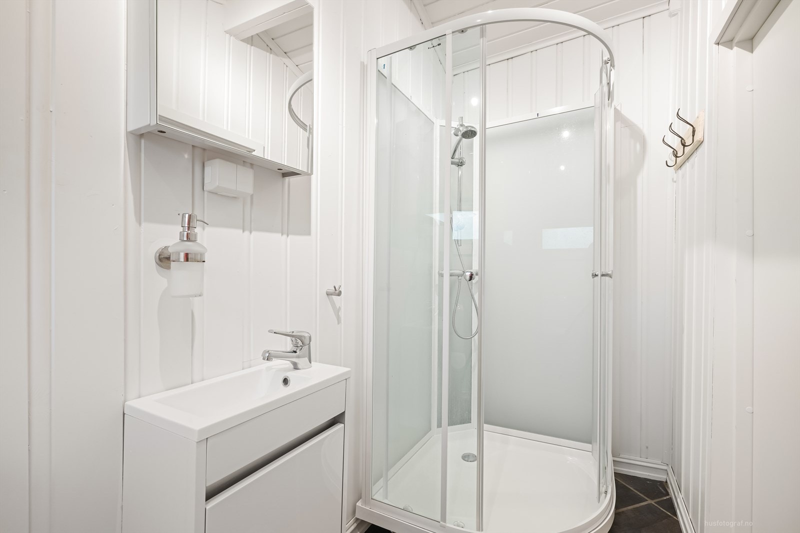 Innredet bad i annekset, utstyrt med servant med skuffer, høyskap, speil med belysning og dusjkabinett. Galleribilde