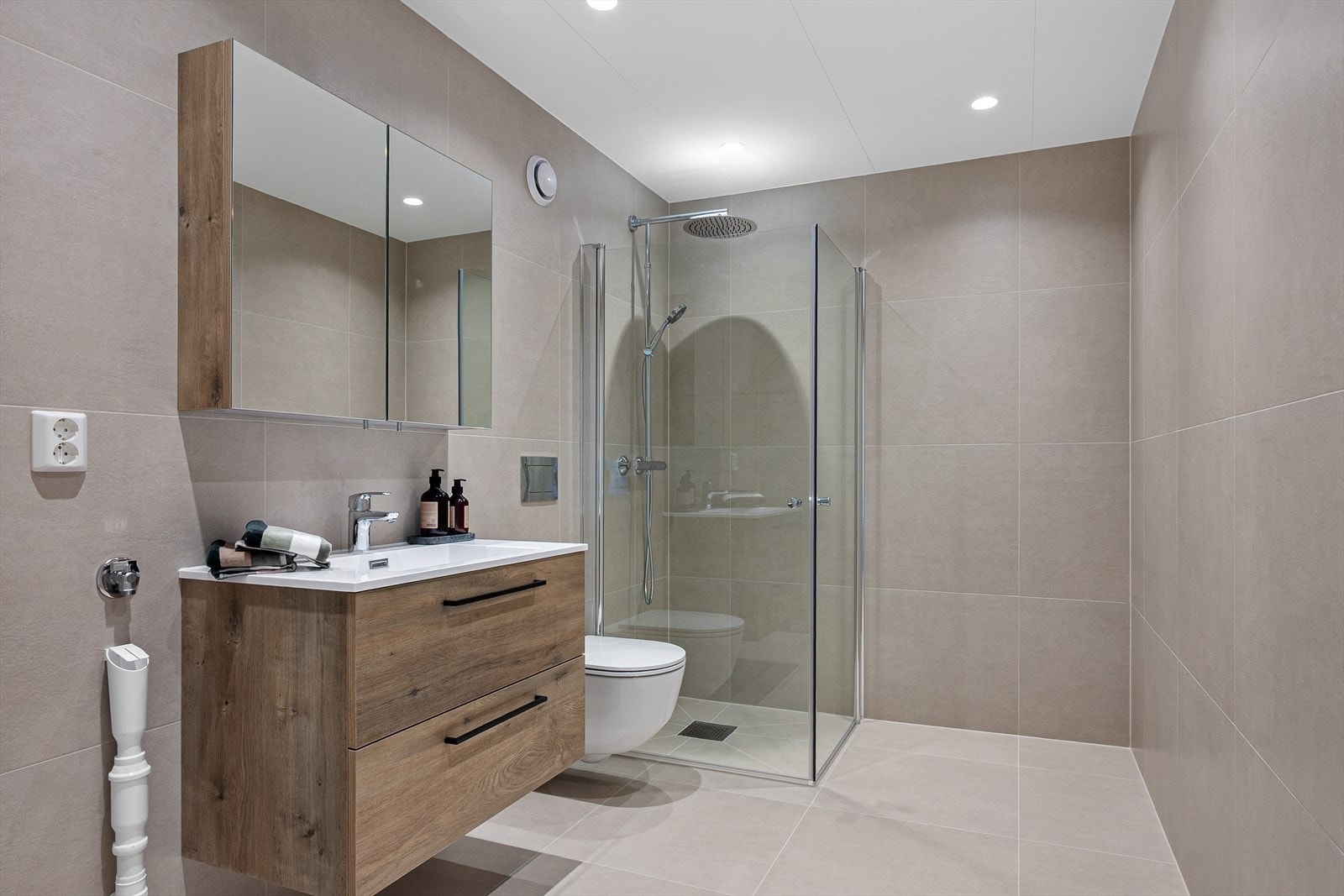 Badet fra 2025 har god størrelse og fremstår delikat og tidløst med flislagte overflater, gulvvarme og downlights. Galleribilde