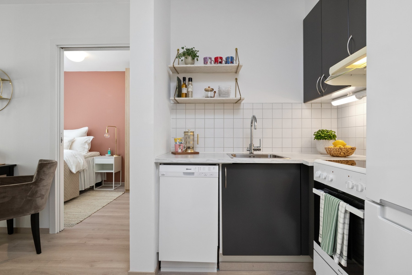 Innredningen har grå, glatte fronter, nedfelt oppvaskkum og hvit benkeplate av laminat i marmormønster. Galleribilde