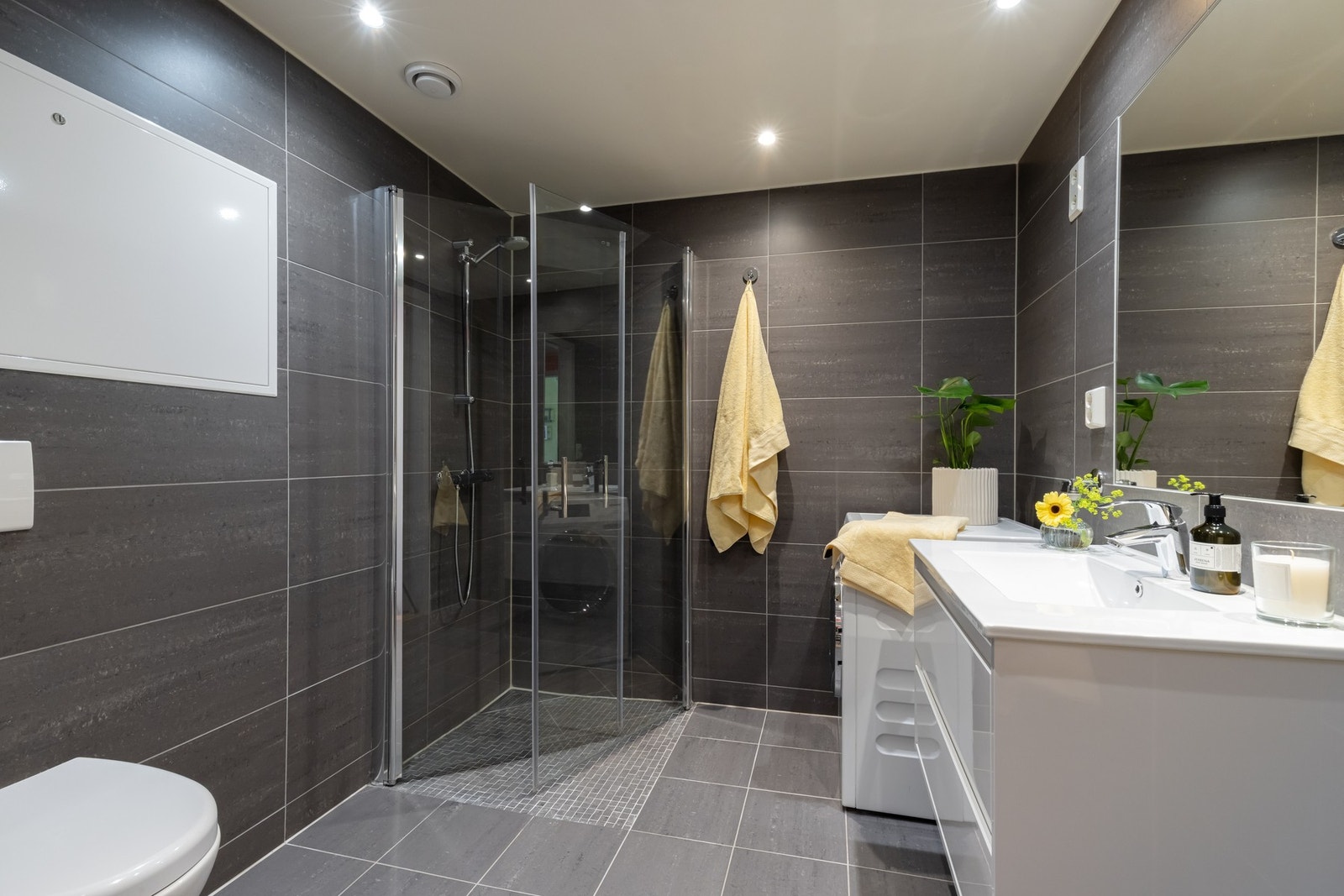 Behagelig, stort og mørkt flislagt baderom med god belysning og gulvvarme. Galleribilde