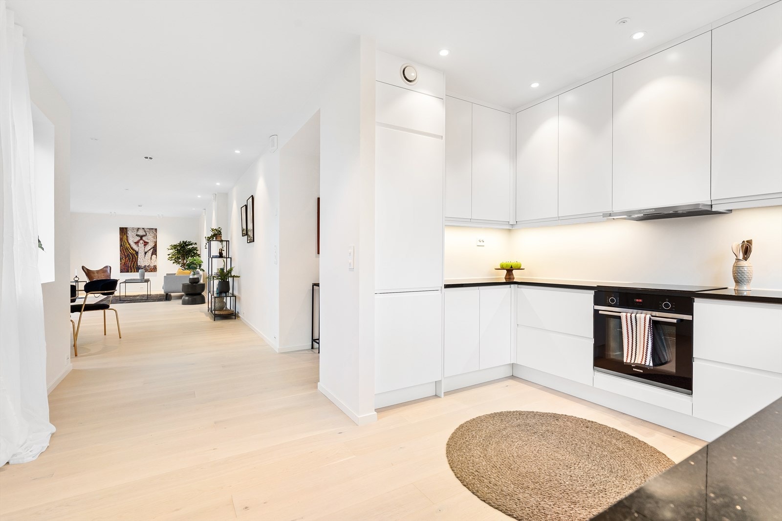 Kjøkkenet er innredet med glatter fronter, lys under overskap, benkeplate i stein, underlimt oppvaskkum med ettgreps armatur fra Grohe. Galleribilde