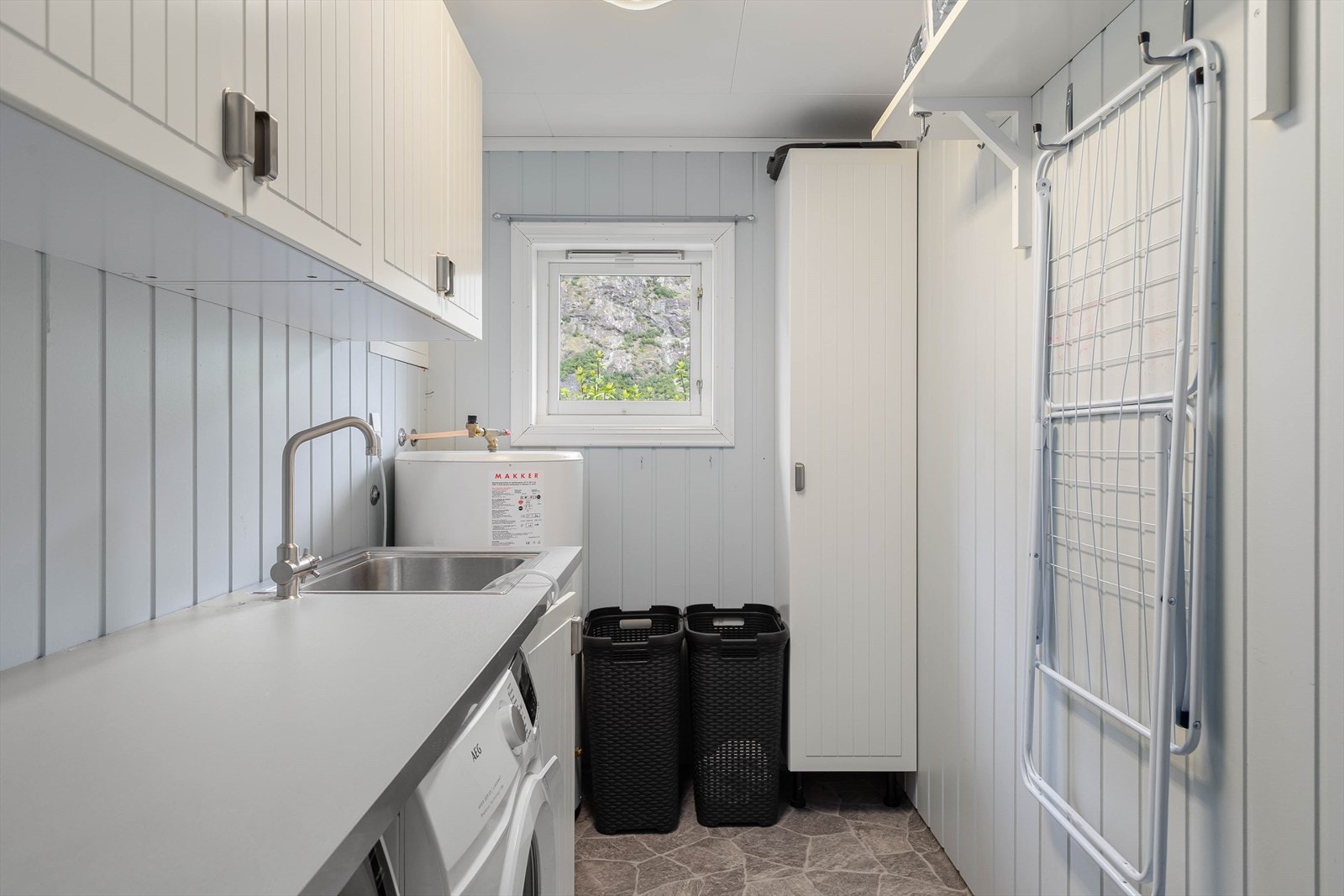 Vaskerommet har vinylbelegg på golv med elektriske varmekabler, malte veggplater og himlingsplater. Rommet har innredning med nedfelt servant og opplegg for vaskemaskin. Galleribilde