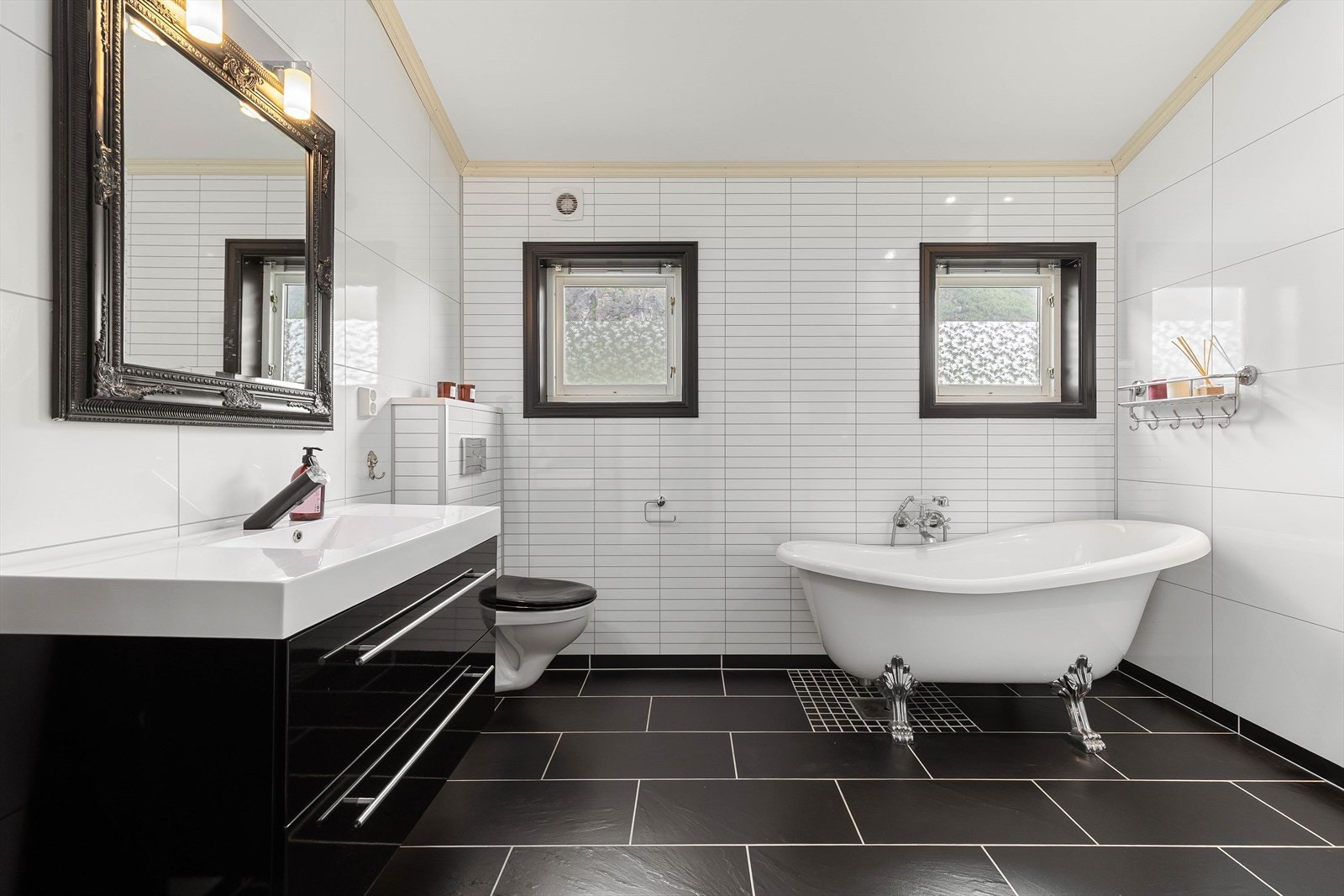 Badet har fliser på golv med varmekabler, baderomsplater på veggar og malt himling. Galleribilde