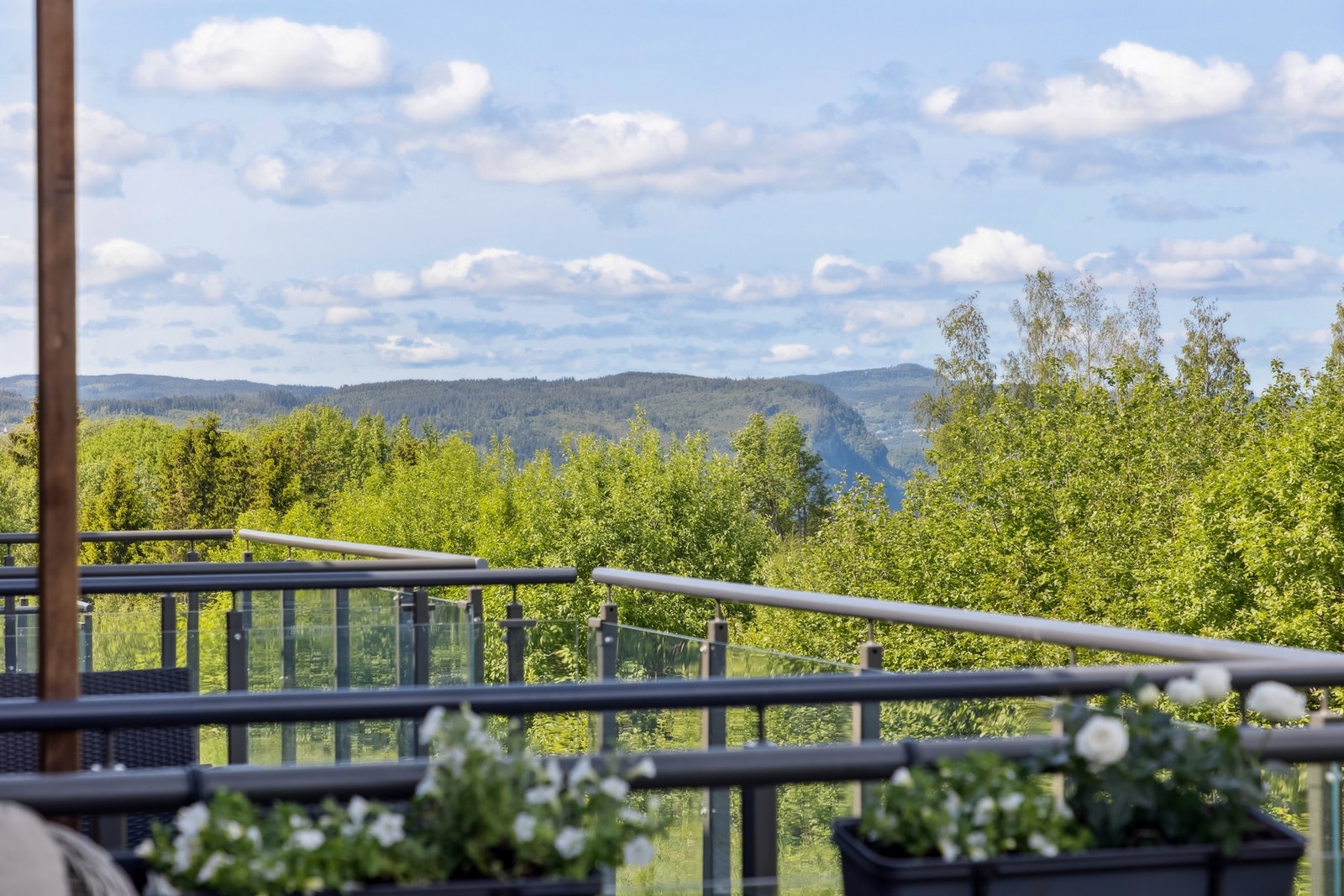 Vestvendt balkong med nydelig utsikt mot grøntområde og åslandskap i horisonten. Galleribilde