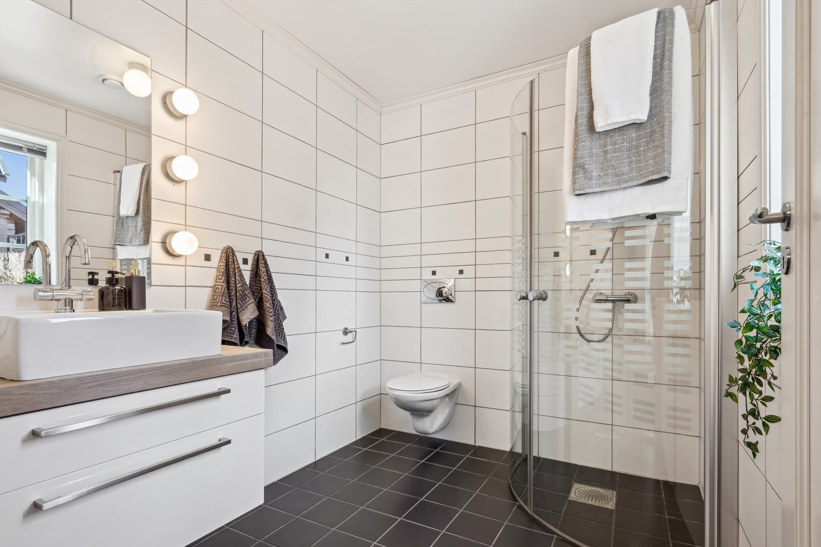 Badet i første etasje ligger i forbindelse med entreen/hallen og har mørke fliser på gulvet og hvite fliser på vegg. Galleribilde