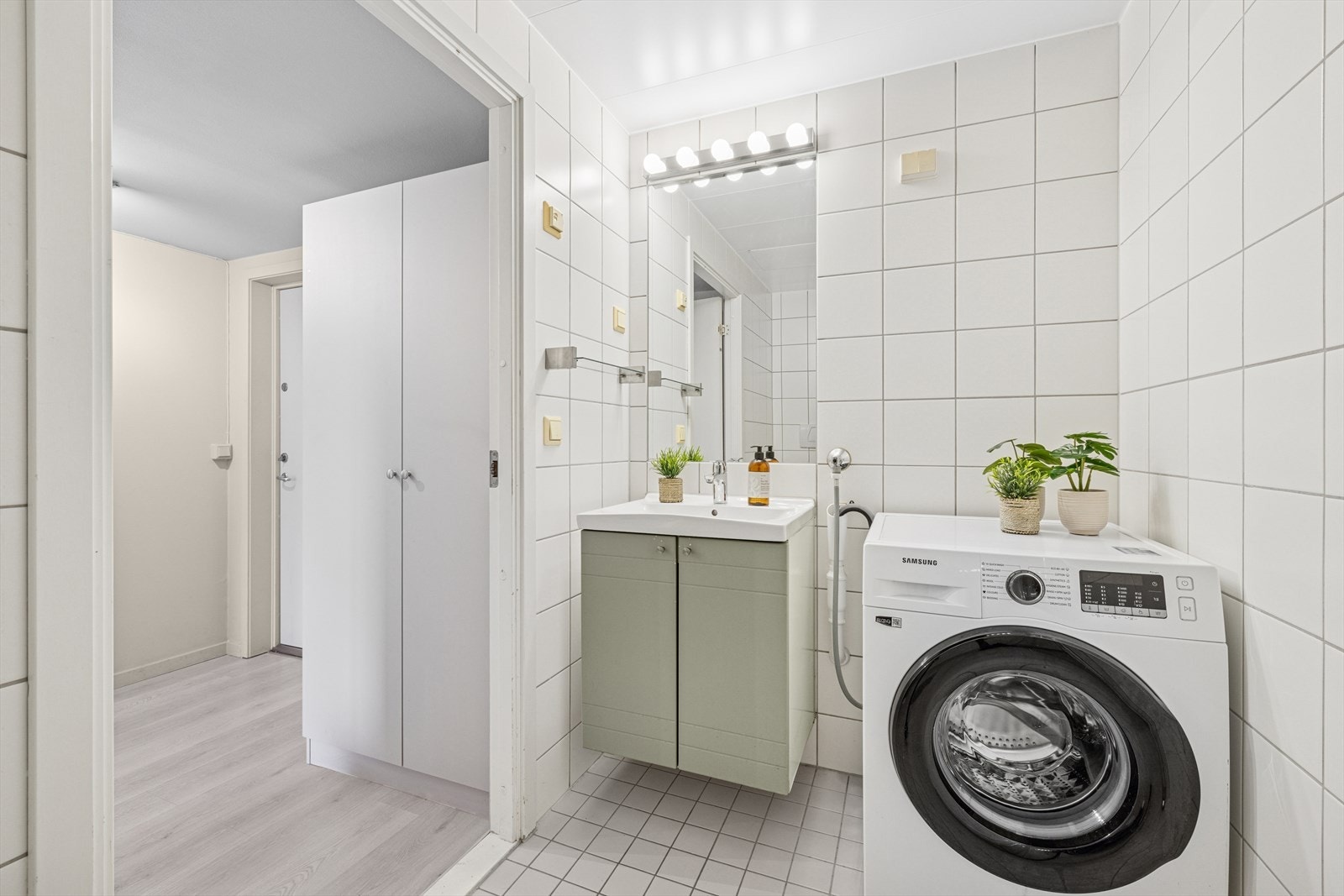 Badet er innredet med veggmontert servantskap og opplegg for vaskemaskin/tørketrommel. Galleribilde