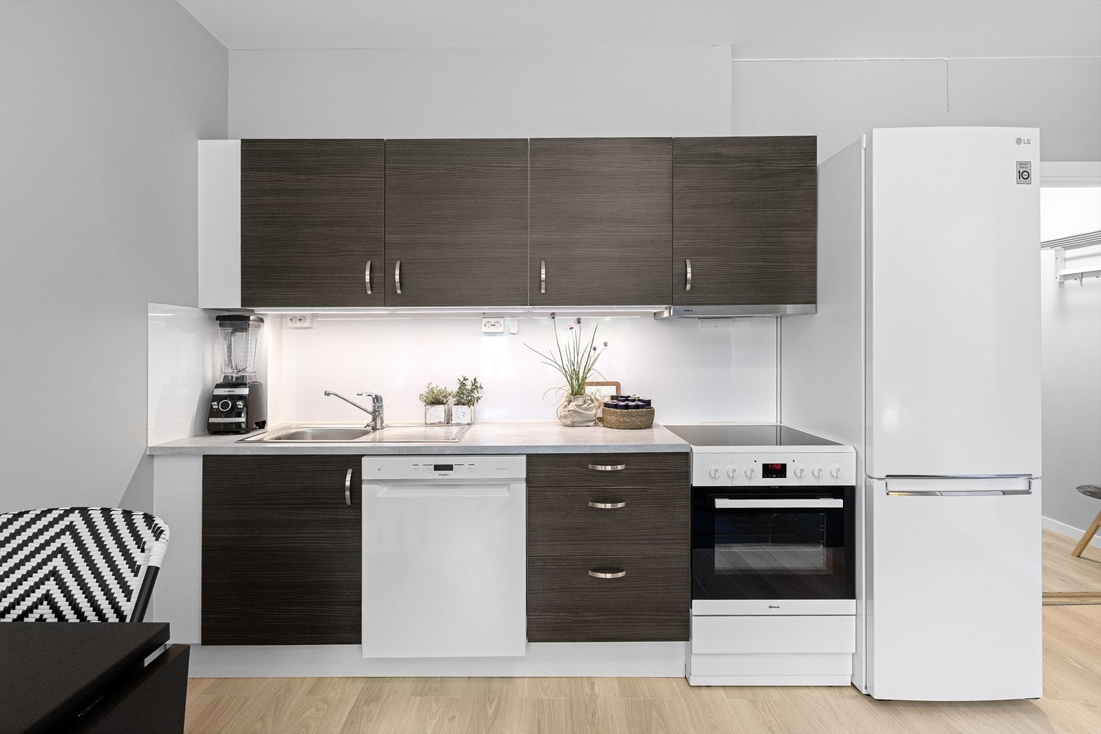 Kjøkkenet har innredning med glatte fronter, benkeplaten er av laminat, og det er vannstoppsystem og komfyrvakt. Kjøkkenventilator med kullfilter. Galleribilde