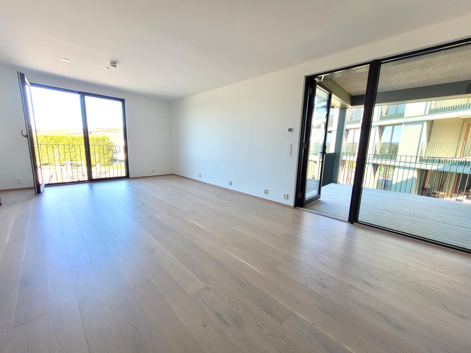 Lys stue med åpen kjøkkenløsning og utgang til overbygd balkong. Galleribilde