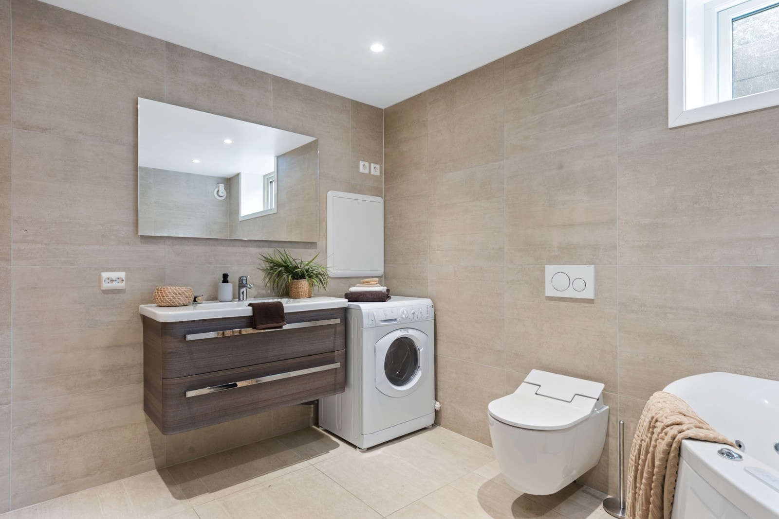 Et delikat bad innredet med badekar, dusjhjørne, servantinnredning og vegghengt toalett. Galleribilde