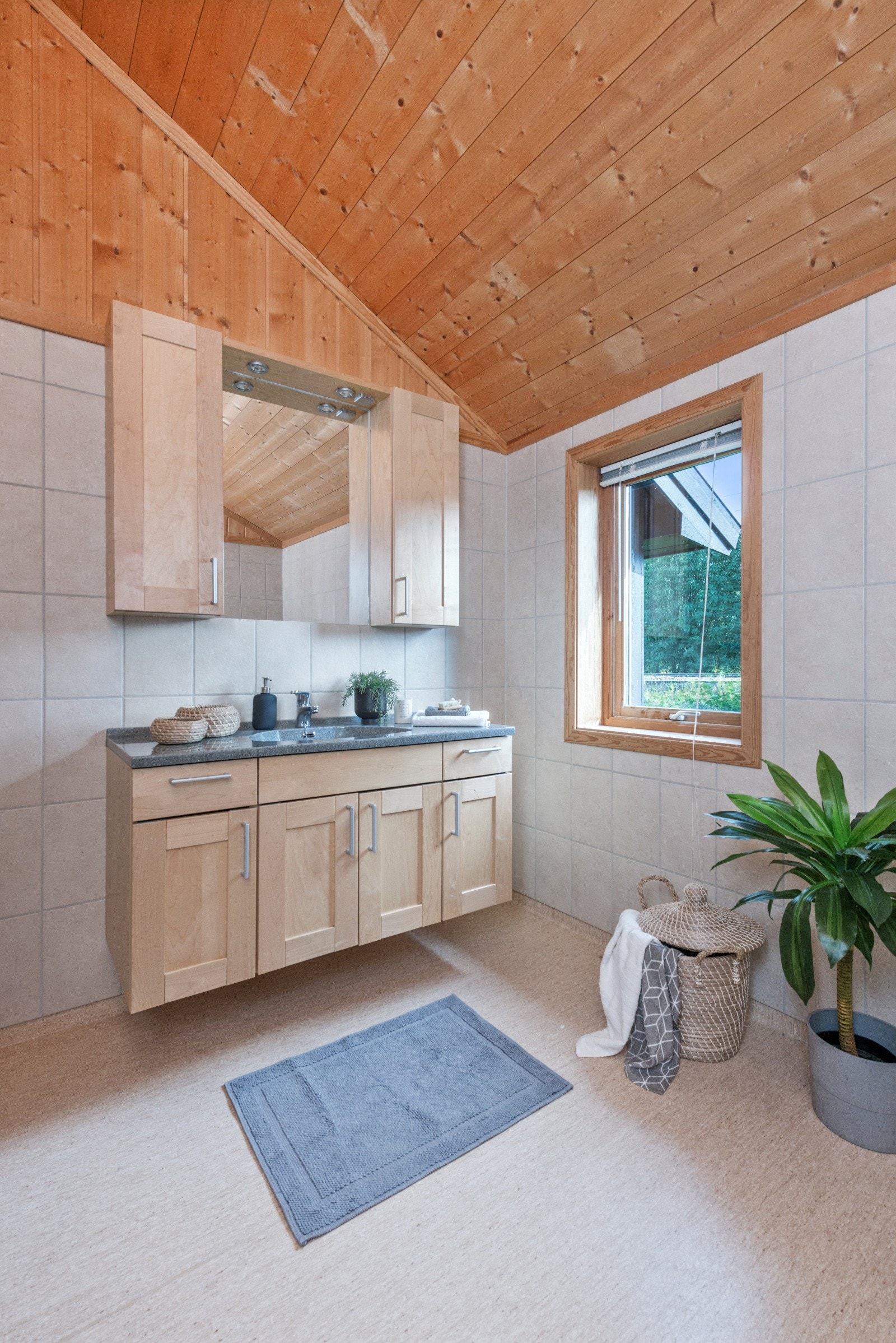 BAdet har fliser på vegger, gulvbelegg på gulv og panel i himling samt øvre del av vegger. Galleribilde