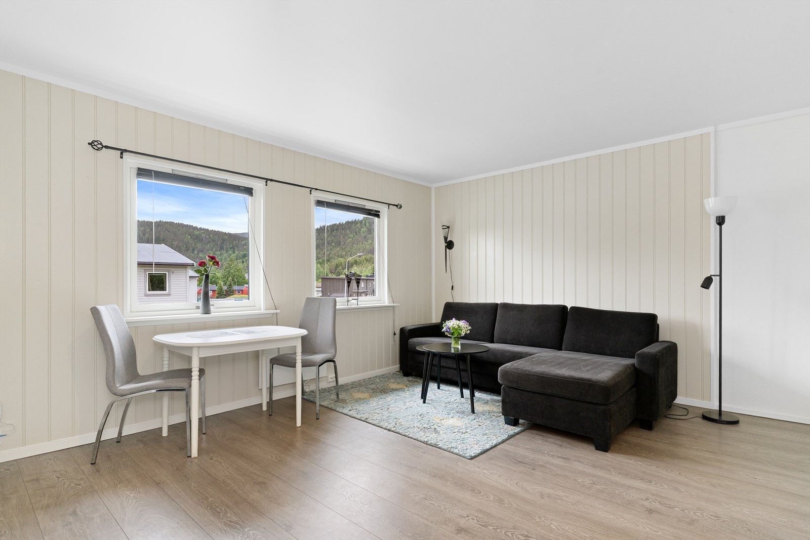Stuen oppleves som lys og innbydende med 1-stavs laminat på gulv og malt panel på vegg malt i en dus fargetone. Galleribilde