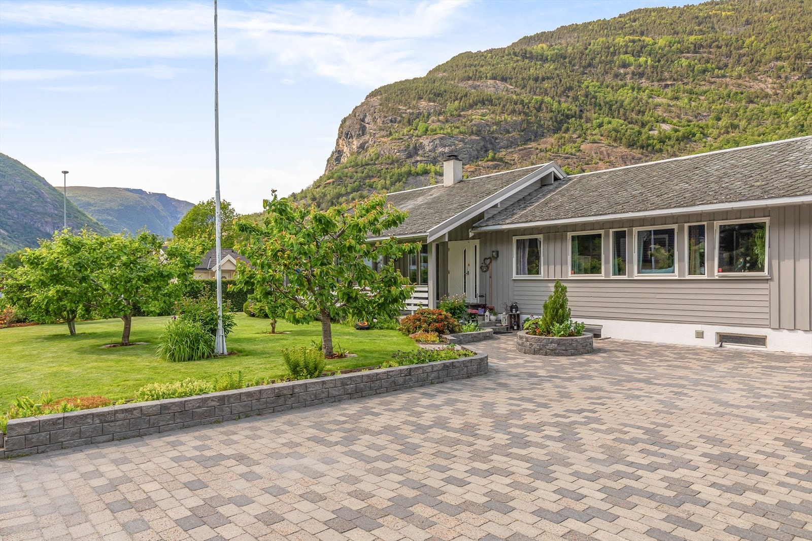 Tunet er fint opparbeida med belegningsstein og gir plass til fleire bilar. Det er også montert el-bil ladar i tunet. Galleribilde