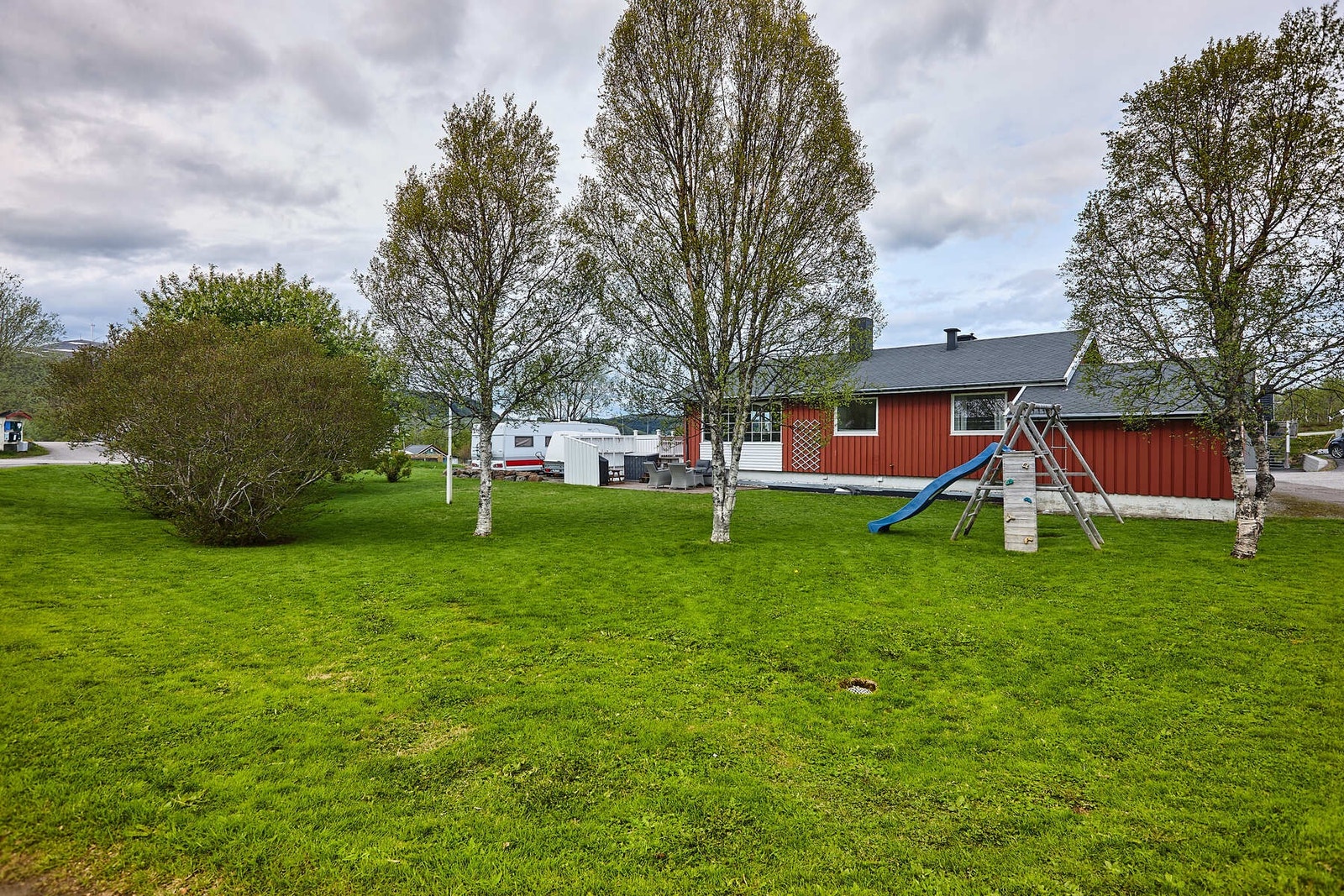 Tomten som er på nesten 1,2 mål er pent opparbeidet med plen, busker og trær. Galleribilde