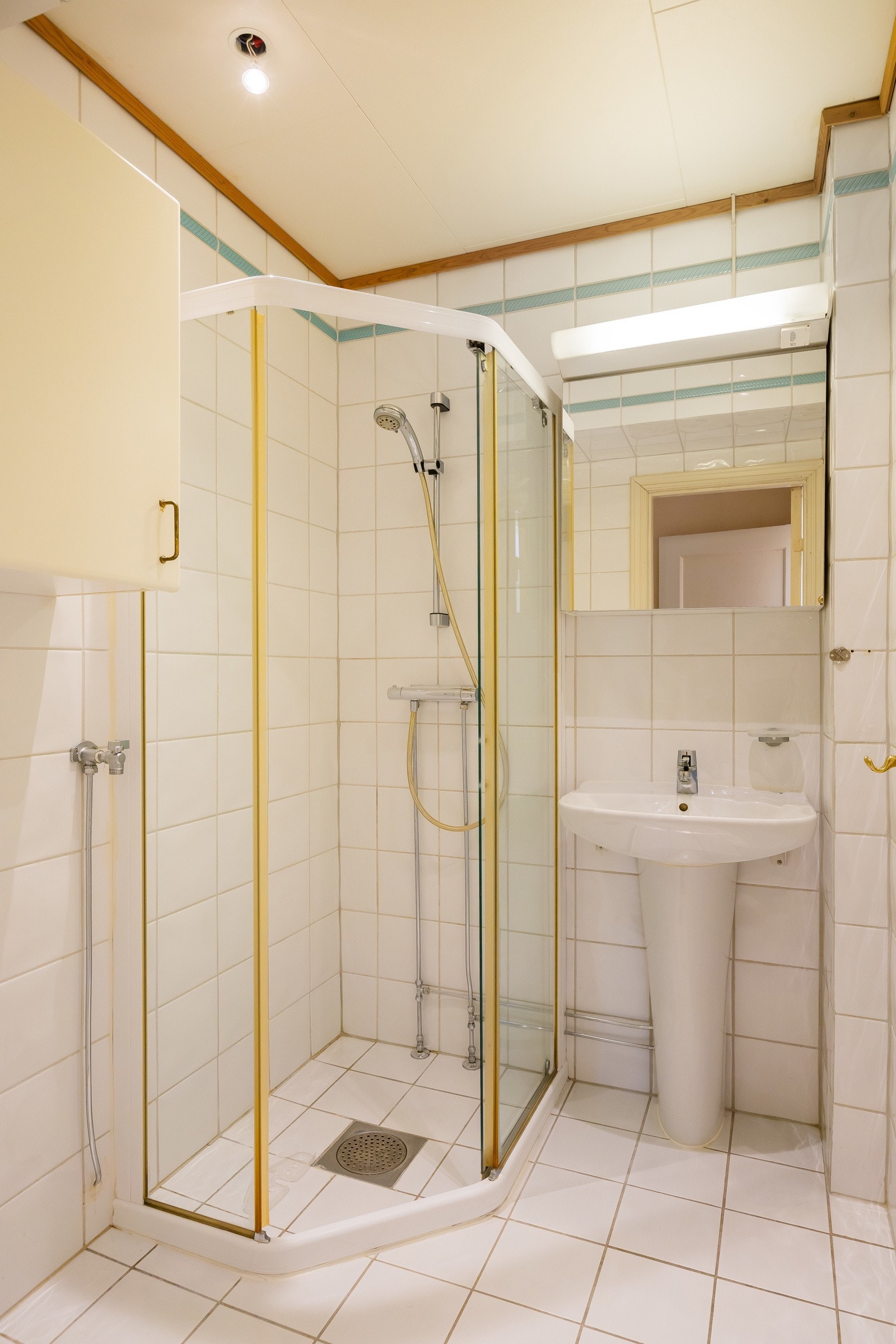 Baderom innredet med dusjhjørne med innfellbare dusjdører og søyleservant med blandebatteri. Opplegg til vaskemaskin Galleribilde