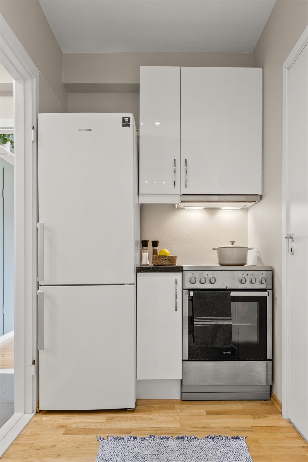 Lys prefabrikert kjøkkeninnredning fra 2012 med høyglans fronter, benkeplate i laminat og nedfelt rund oppvaskkum i rustfritt stål. Galleribilde