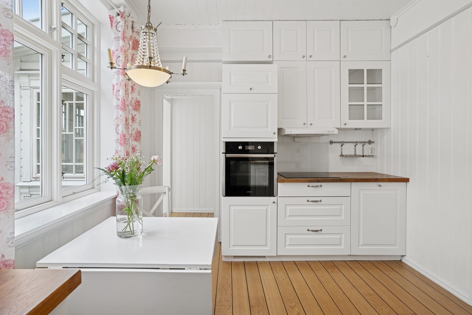 Takhøy kjøkkeninnredning med hvite profilerte fronter og enkelte overskap i glass. Galleribilde