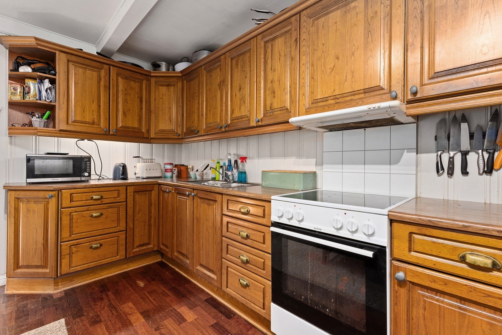 Kjøkken med fabrikkframstilt innredning med over og underskaper. Fronter i overflatebehandlet naturtre. Utstyr: Avsatt plass til komfyr og kjøleskap. Kjøkkenventilator med avkast ut. Galleribilde