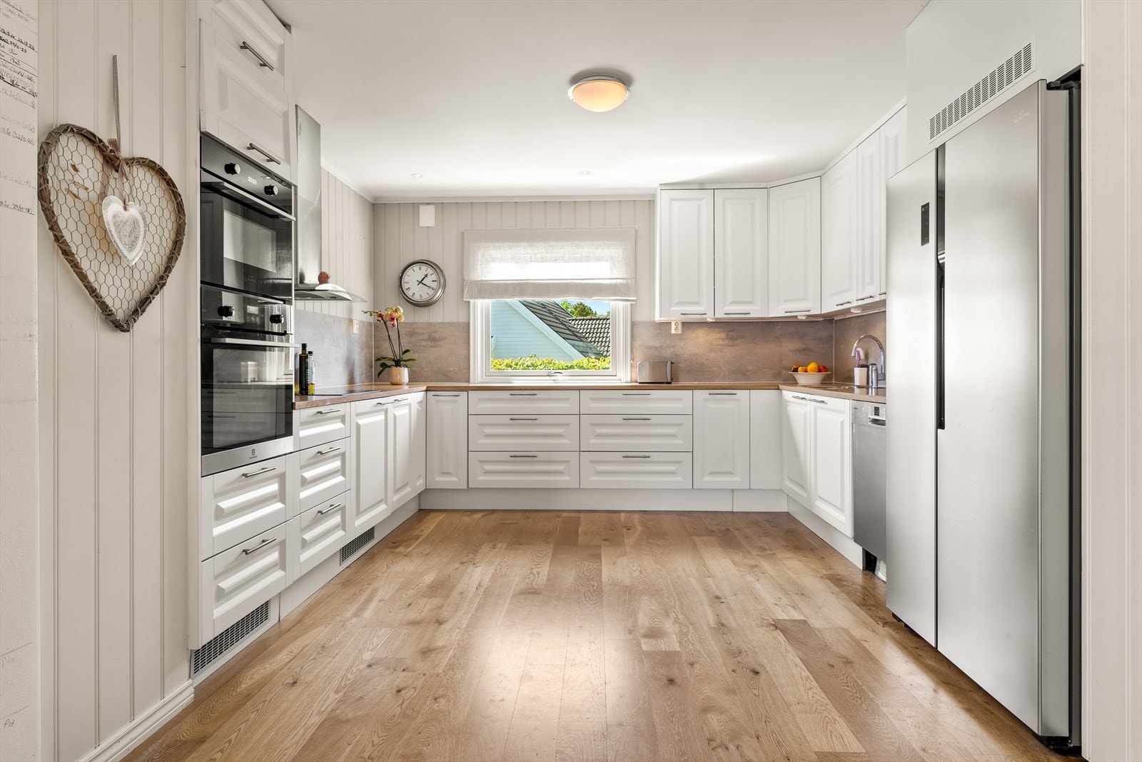Lyst og lekkert kjøkken innredet med profilerte fronter, laminat benkeplate med nedfelt vaskekum. Splashboard og belysning over benkeplaten. Takhøye overskap. Galleribilde