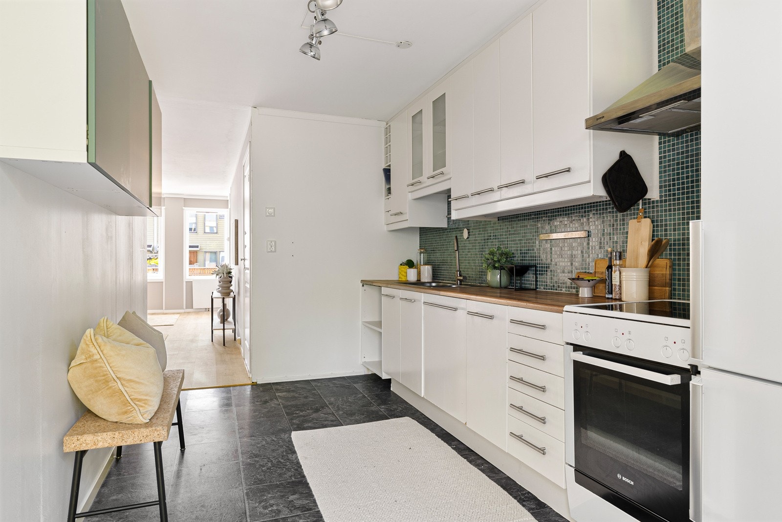 Kjøkkenet har hvite fronter og et tidløst uttrykk, med takhøye overskap, dobbel vaskekum, samt rikelig med oppbevaringsplass i skap og skuffer. Galleribilde