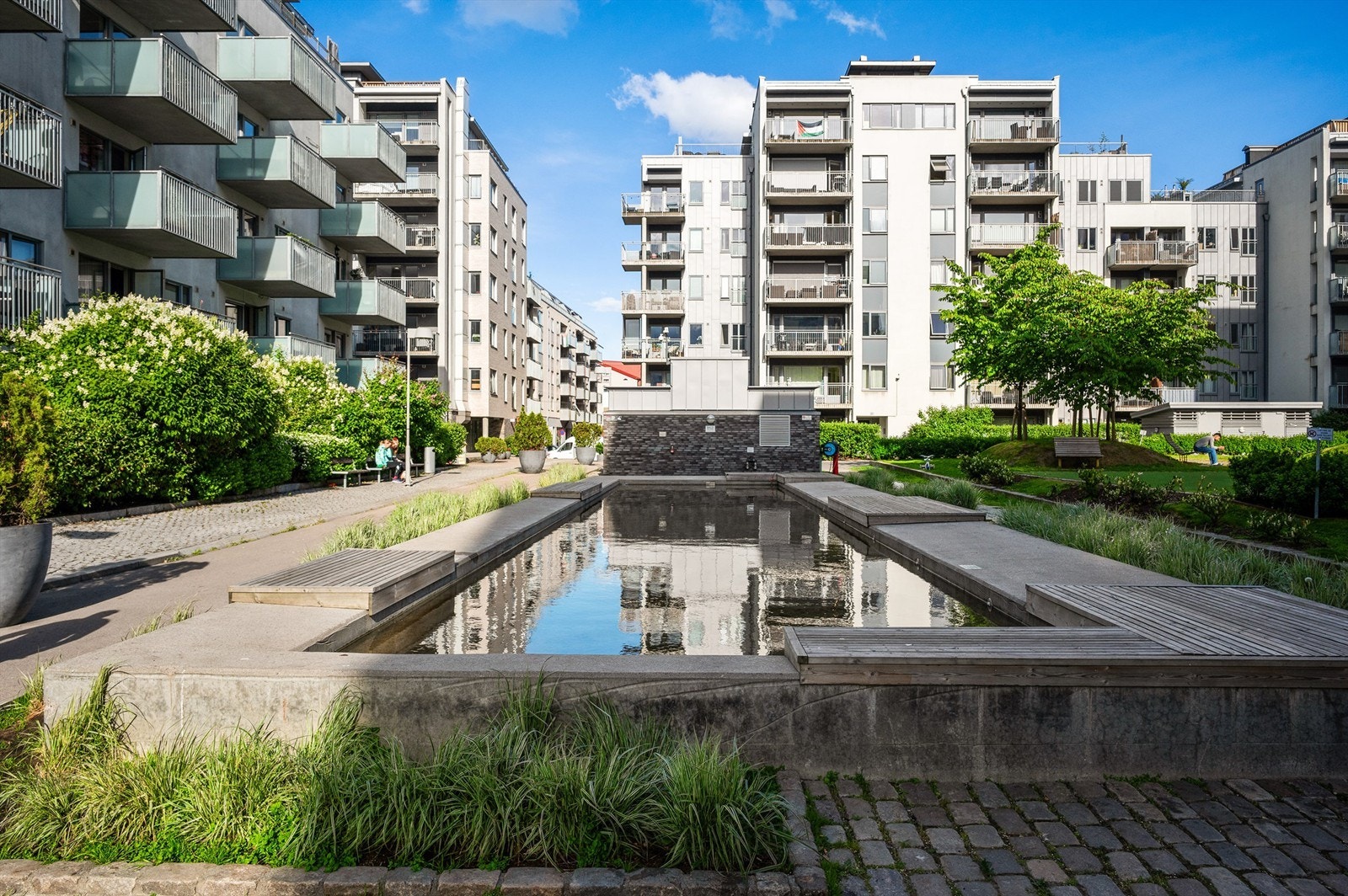 Pent opparbeidet fellesarealer med gressplener, beplantning, lekeplass og asfalterte gangveier. Galleribilde