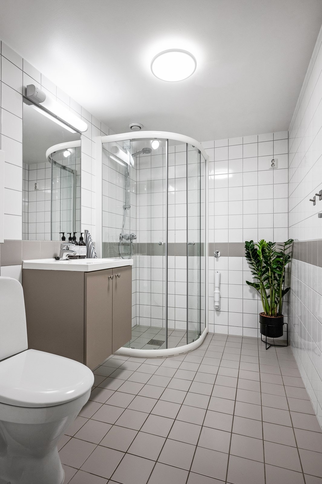 Delikat baderom med flislagte overflater og varme i gulvet for en lun og behagelig start på dagen. Galleribilde