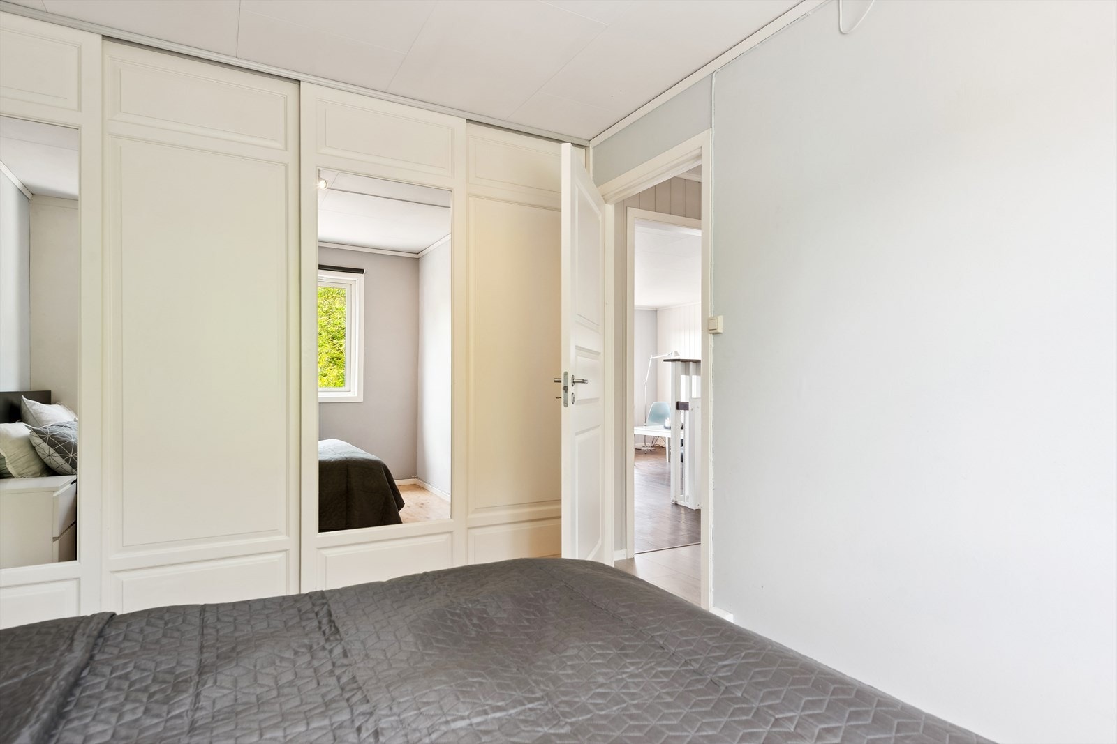 Rommet er utstyrt med en praktisk skyvedørsgarderobe som gir rikelig med oppbevaringsplass uten å oppta unødvendig gulvareal - en smart og stilren løsning for en ryddig hverdag. Galleribilde