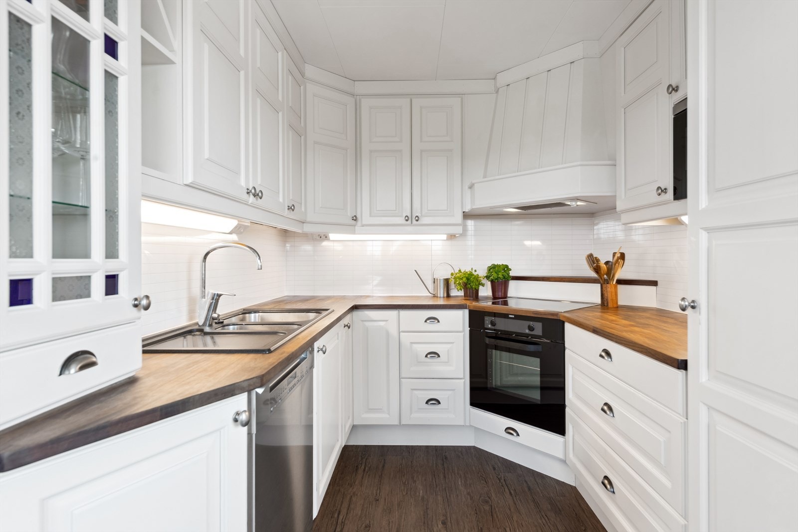 Kjøkkenet har en stilren innredning med profilerte fronter og heltre benkeplate. Vitrineskap med glassfront tilfører et elegant preg. Galleribilde