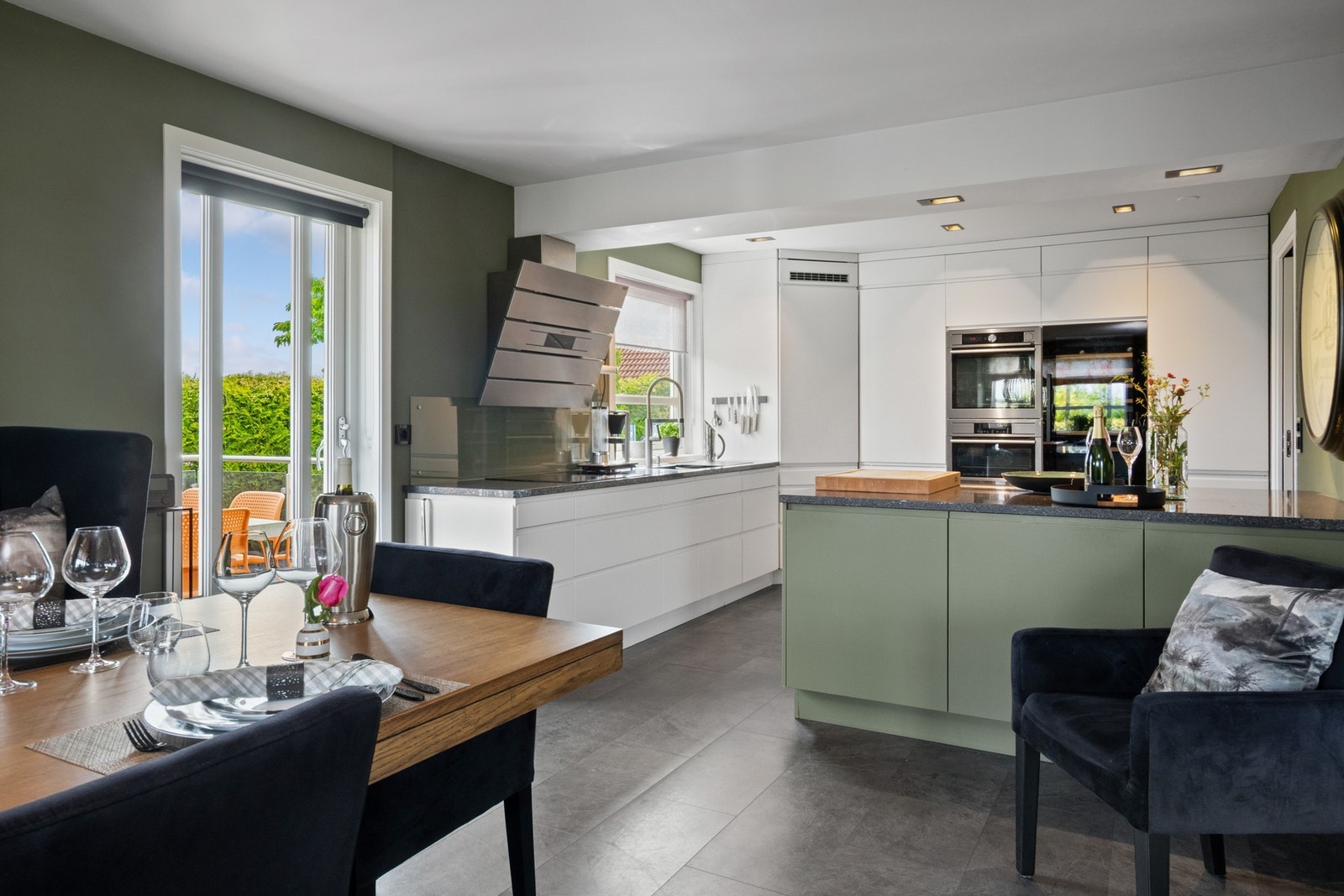 Innredningen har hvite og grønne fronter, takhøye skap og sort benkeplate i granitt med planlimt, matchende kum. Galleribilde