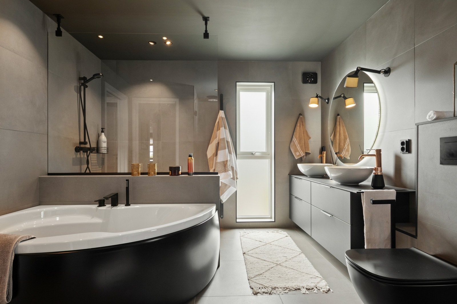 Her er det grå himling med downlights, store, grå fliser på veggene og matchende fliser på gulv med gulvvarme. Galleribilde