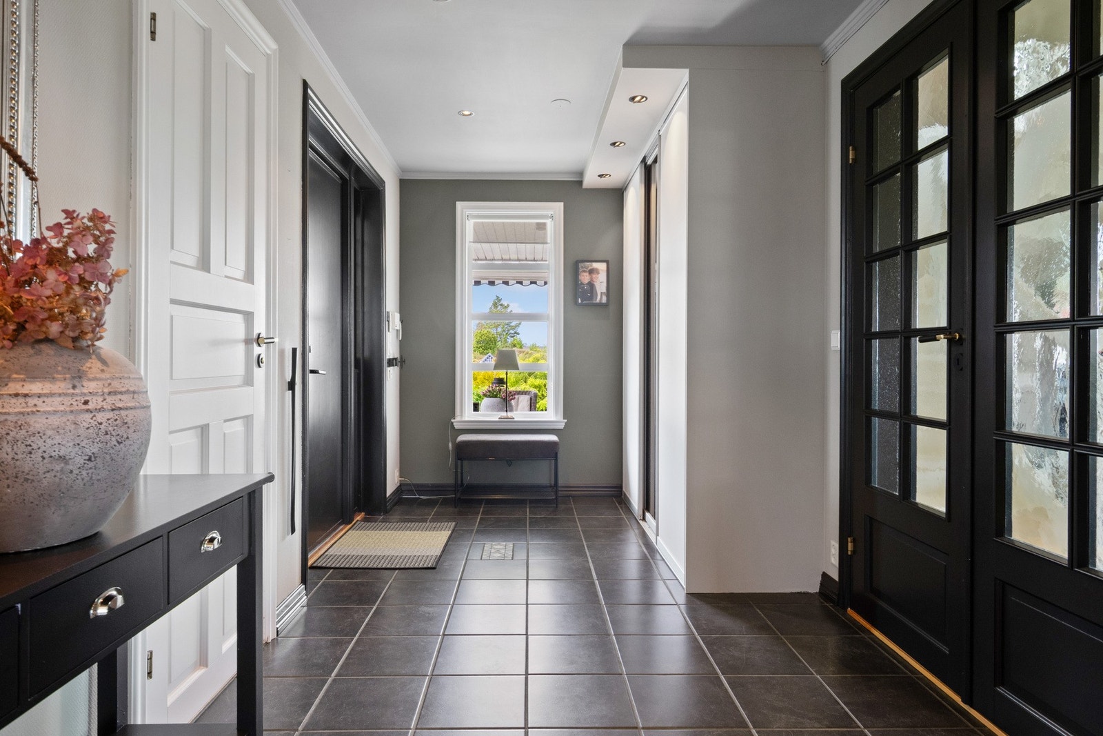 Vel inne blir vi ønsket velkommen i en flott entré med glatte, malte vegger, downlights i himlingen og koksgrå fliser på gulvet. Galleribilde