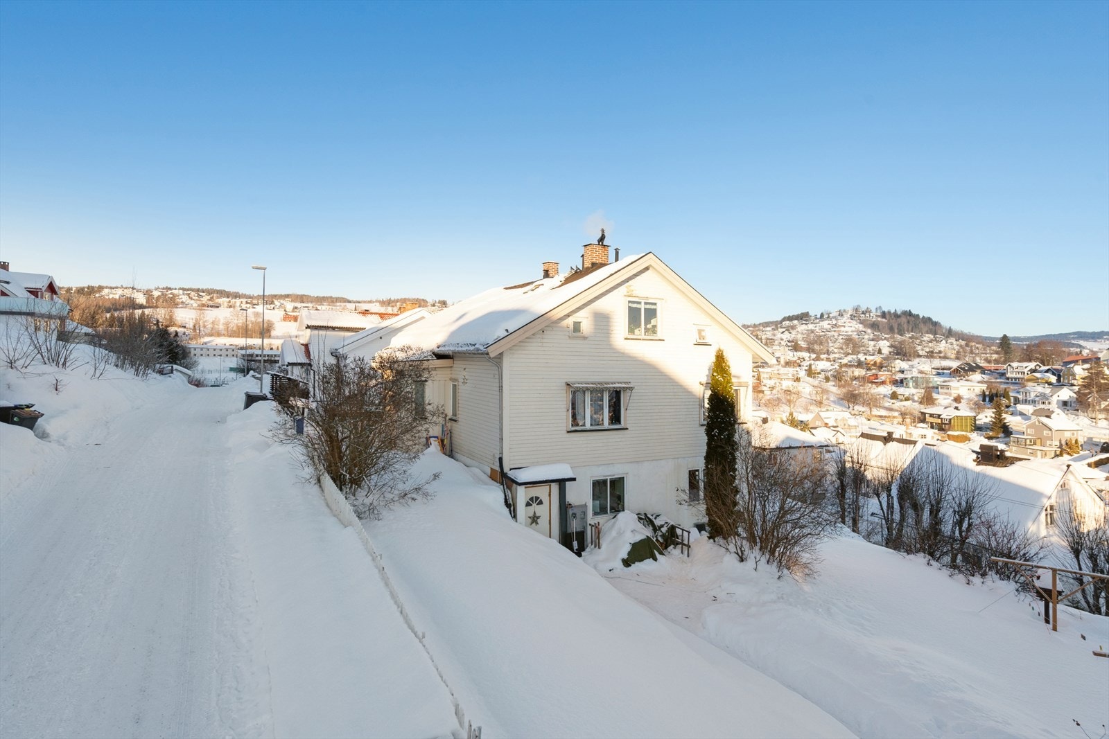 Tomten er skrånende og terrassert, opparbeidet med gjerde, gressplen, diverse beplantninger og en gruset gårdsplass. Galleribilde