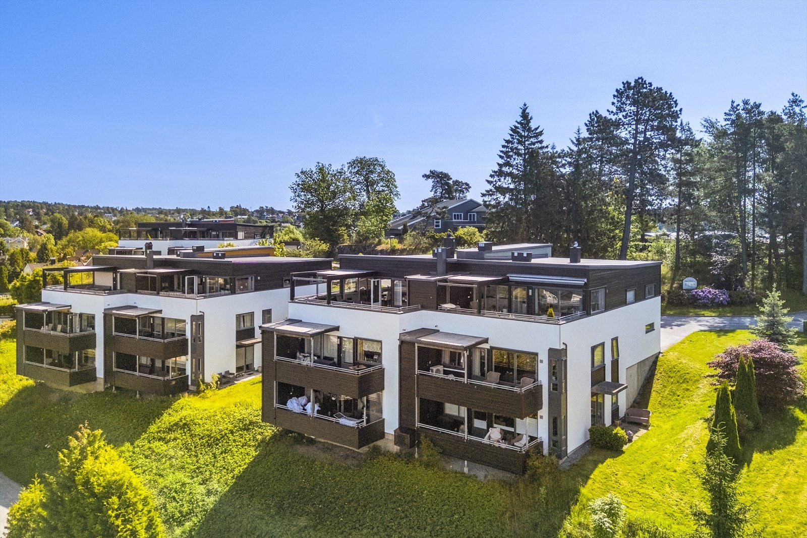 Tomten er solrik og pent opparbeidet med asfalterte gårdsplasser og parkeringsplasser, hageareal med gressplen og beplantning, samt uteplasser med sittegrupper Galleribilde