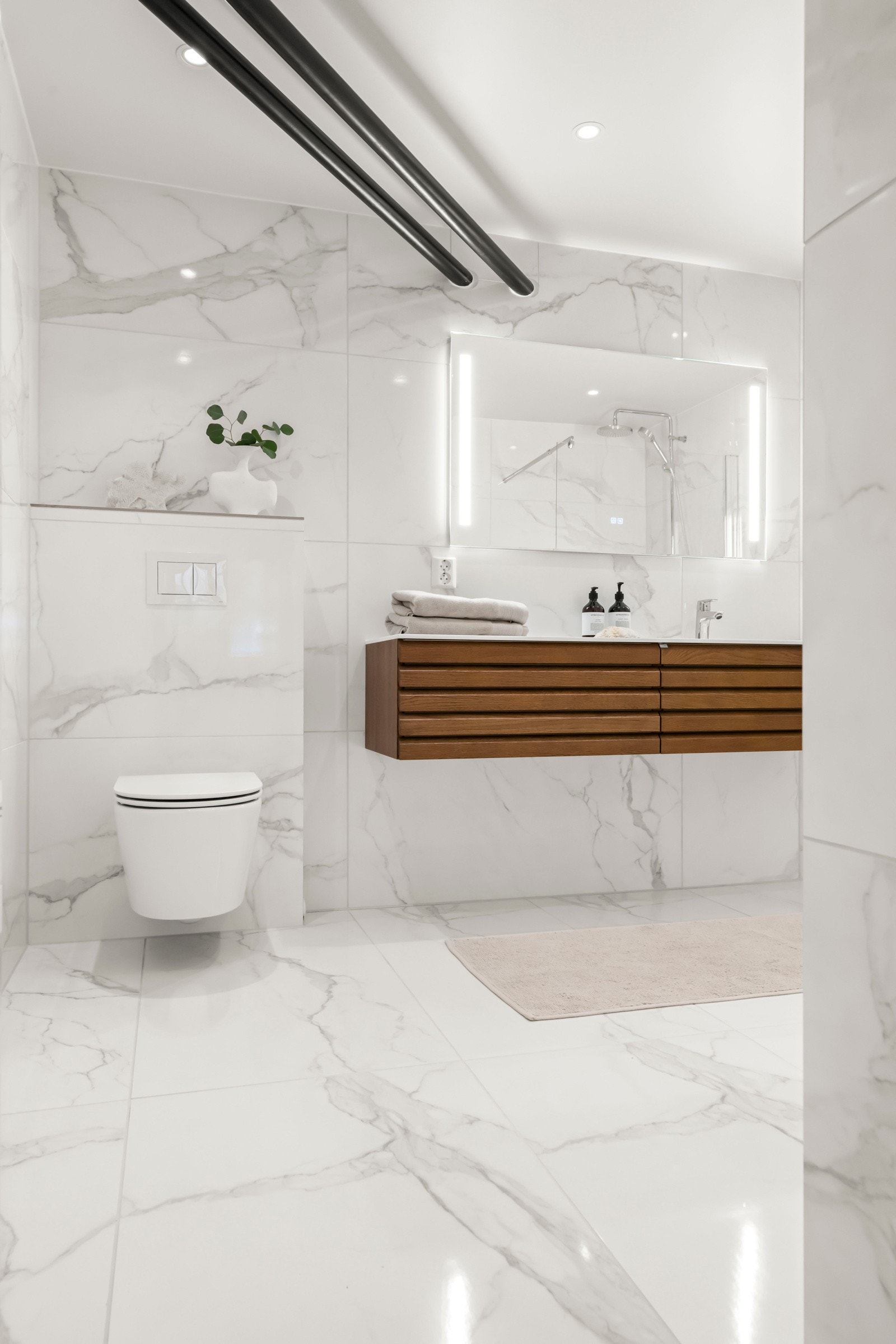 Delikate fliser fra Porcellanato i 120 x 60 cm format på vegger. Gulv også med 120 x 60 cm fliser og 5 x 5 cm fliser i nedsenket dusjområde. Galleribilde