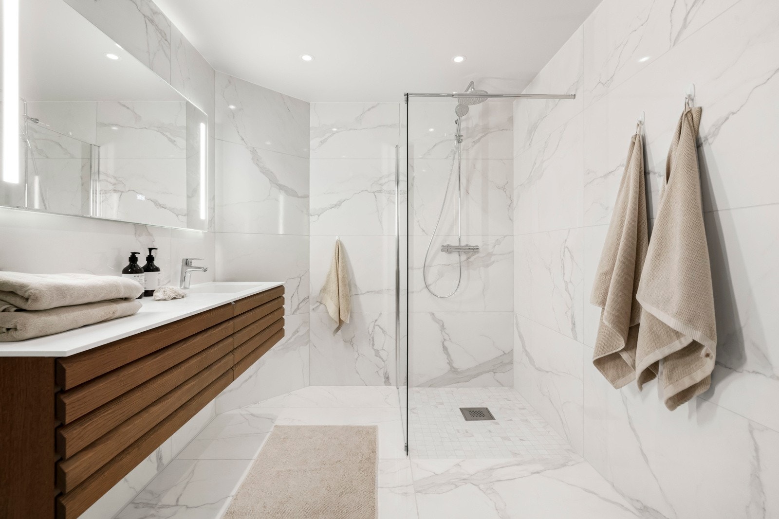 Dusjhjørne med nedfelt gulv i dusjsonen, fastmontert dusjvegg (Celeste). Dusjen er utstyrt med regnfallsdusj og håndholdt dusj. Galleribilde