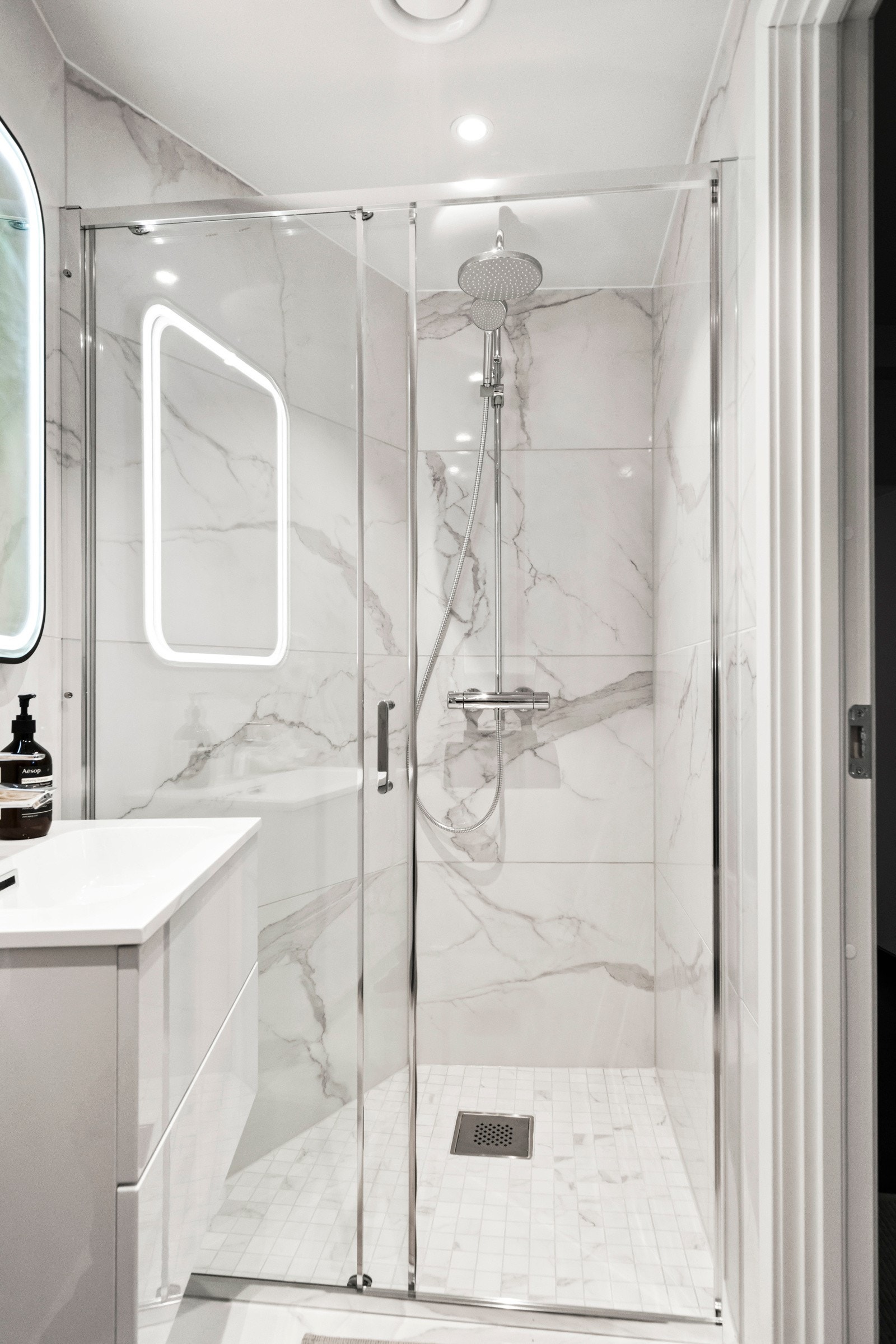 Dusj med fast glassvegg og glass-skyvedør. Dusjen er utstyrt med både regnfallsdusj og håndholdt dusj. Det er nedfelt gulv i dusjsonen. Galleribilde