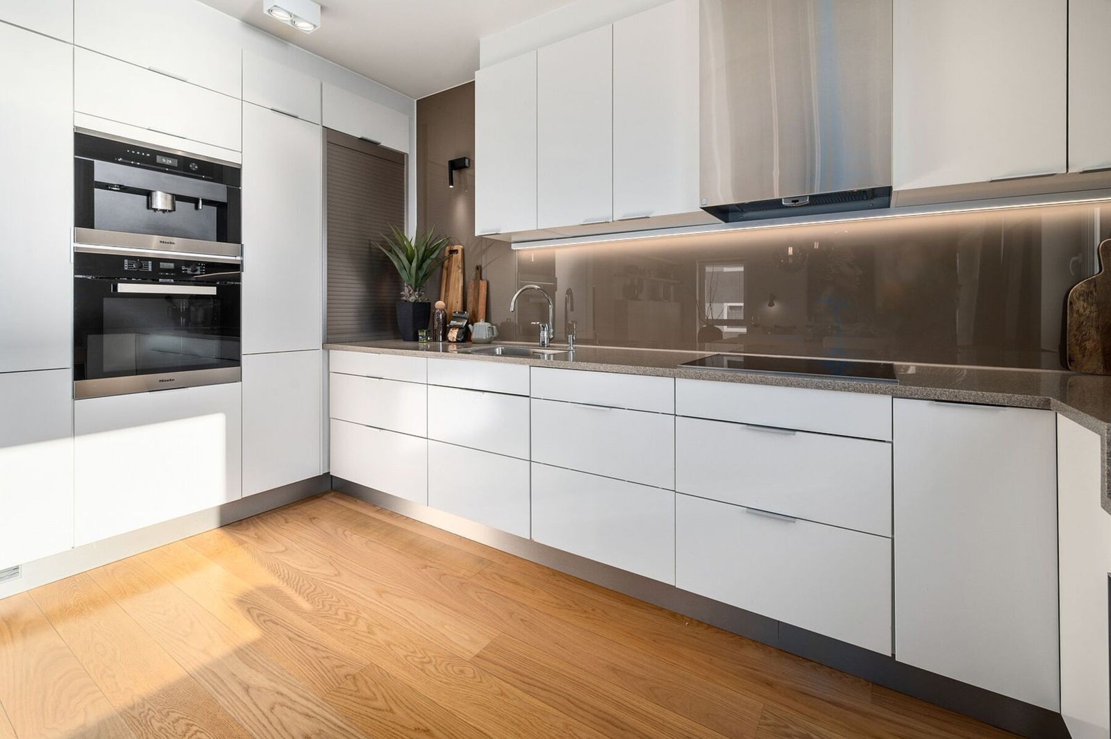 Stilrent kjøkken utstyrt med hvitevarer fra Miele (innebygd kaffemaskin, ovn, vinkjøler, platetopp) Galleribilde