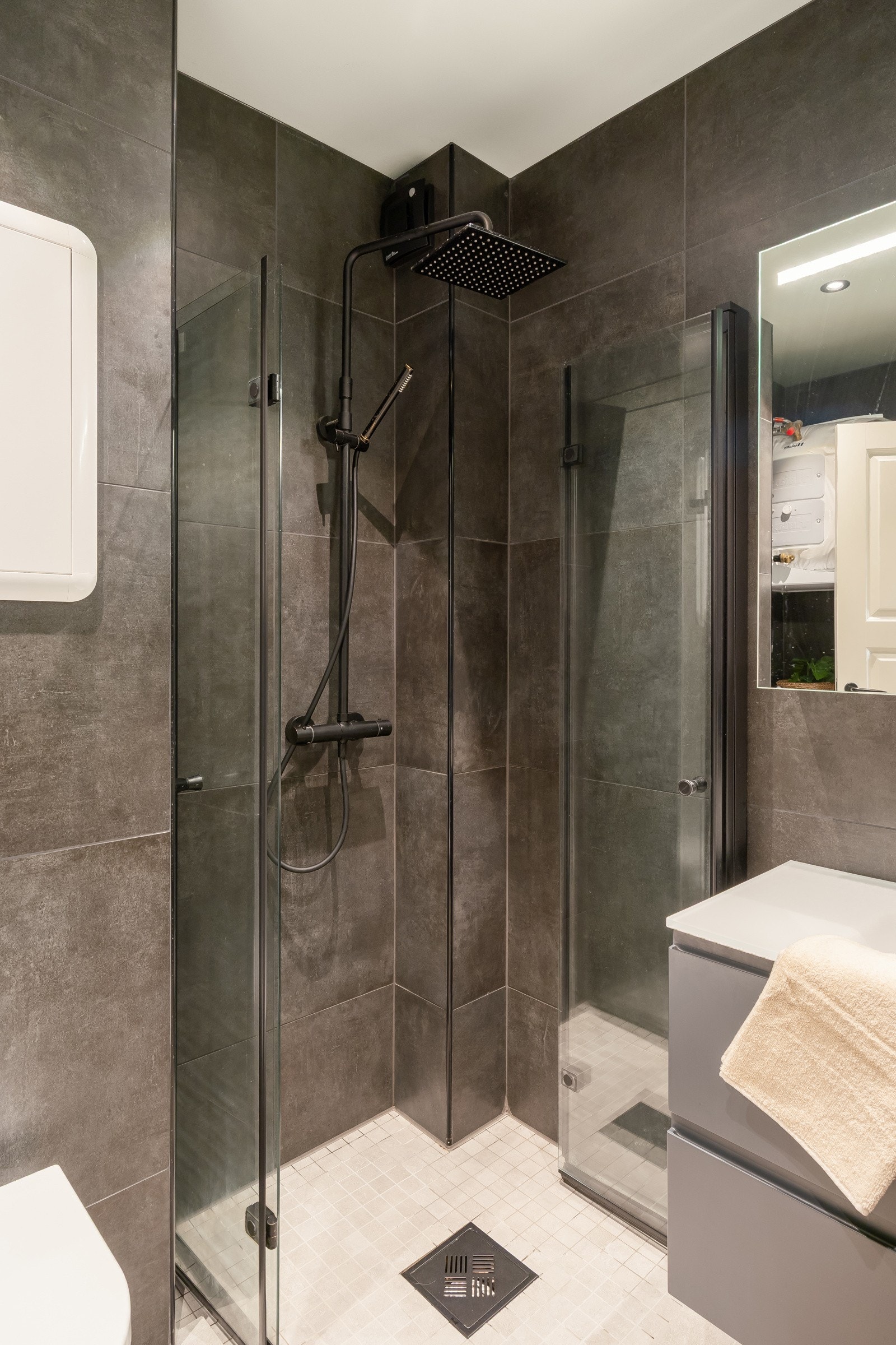 Badet er utstyrt med servant med skuffer, god lagringskapasitet, speilskap, dusjhjørne med innfellbare dører og vegghengt toalett. Galleribilde