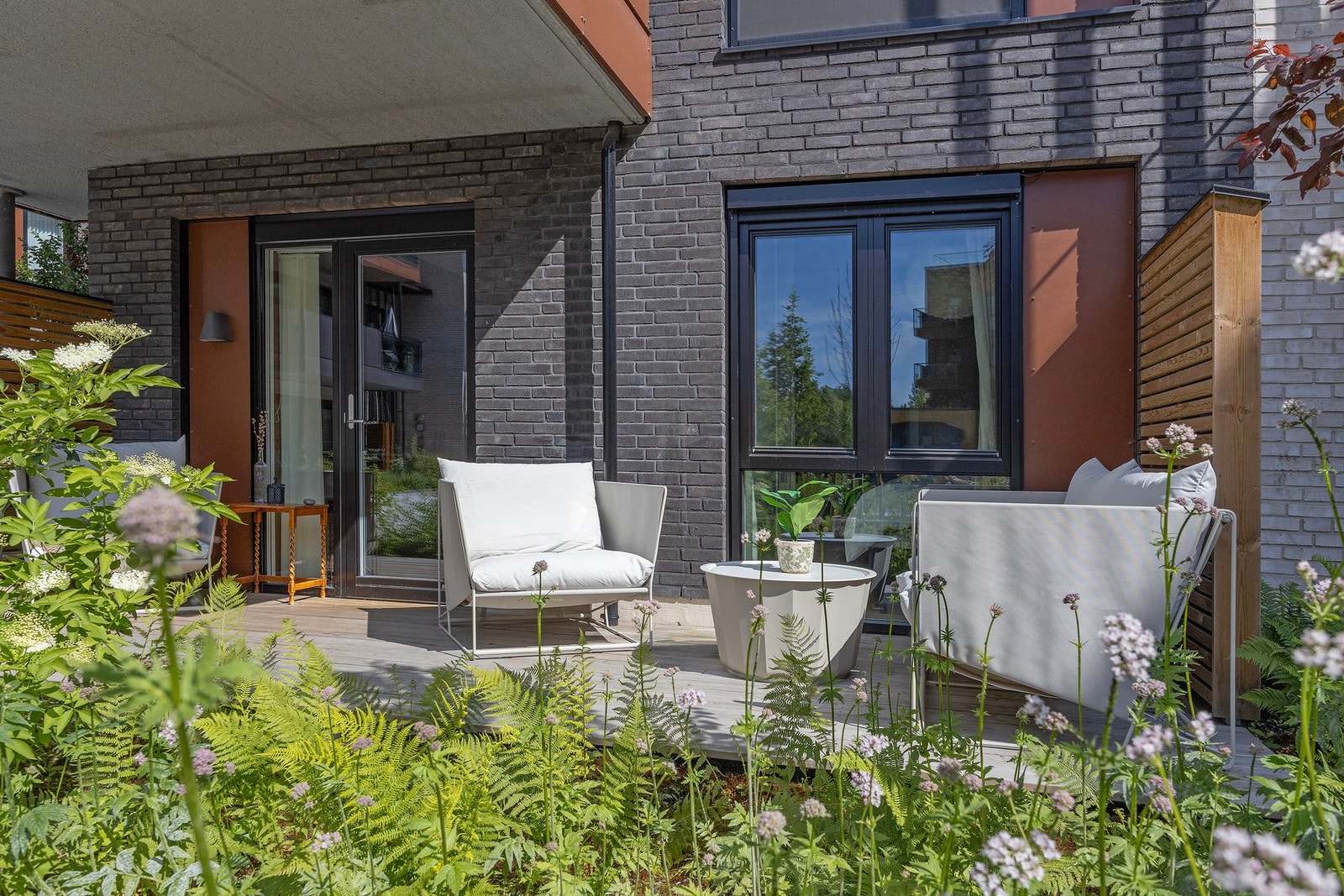 Den ene terrassen vender ut mot et grønt og flott gårdsrom med beplanting, sittegruppe og lekeplass. Galleribilde
