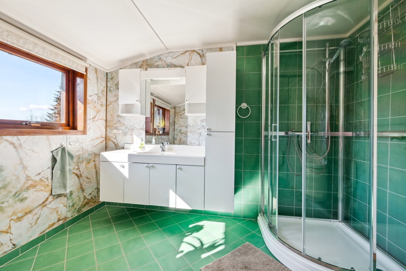 Badet har flislagt gulv med varmekabler. Baderomsplater og flislagte veggflater, og tapetsert himlingsflate Galleribilde