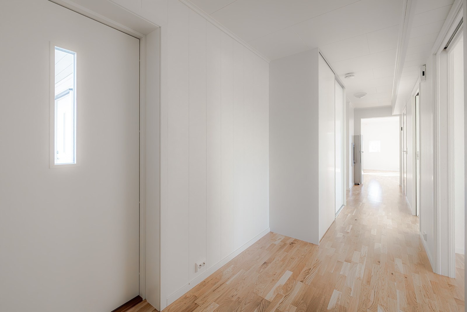 Elementpipe i enden av gangen mot stuen med lukket peisinnsats med glassdør. Galleribilde