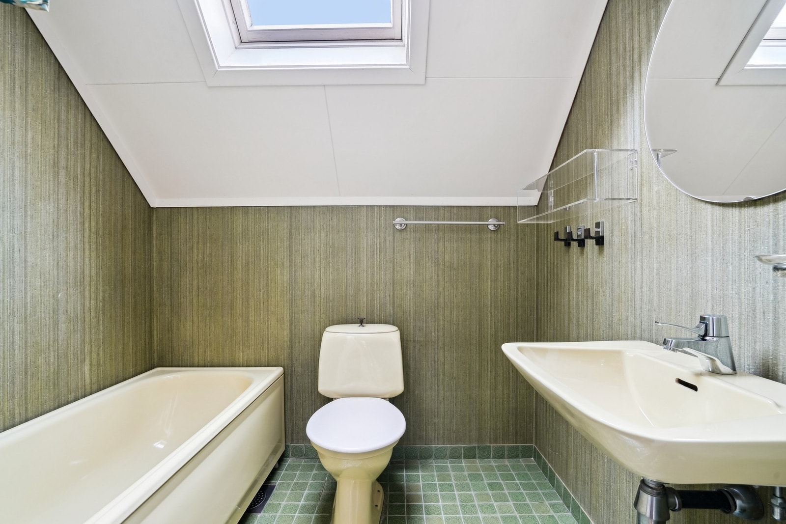 Badet har fliser på gulv og tapet på vegger. Utstyrt med toalett, badekar med dusjgarnityr og vask. Rommet er vurdert klar for rehabilitering. Galleribilde