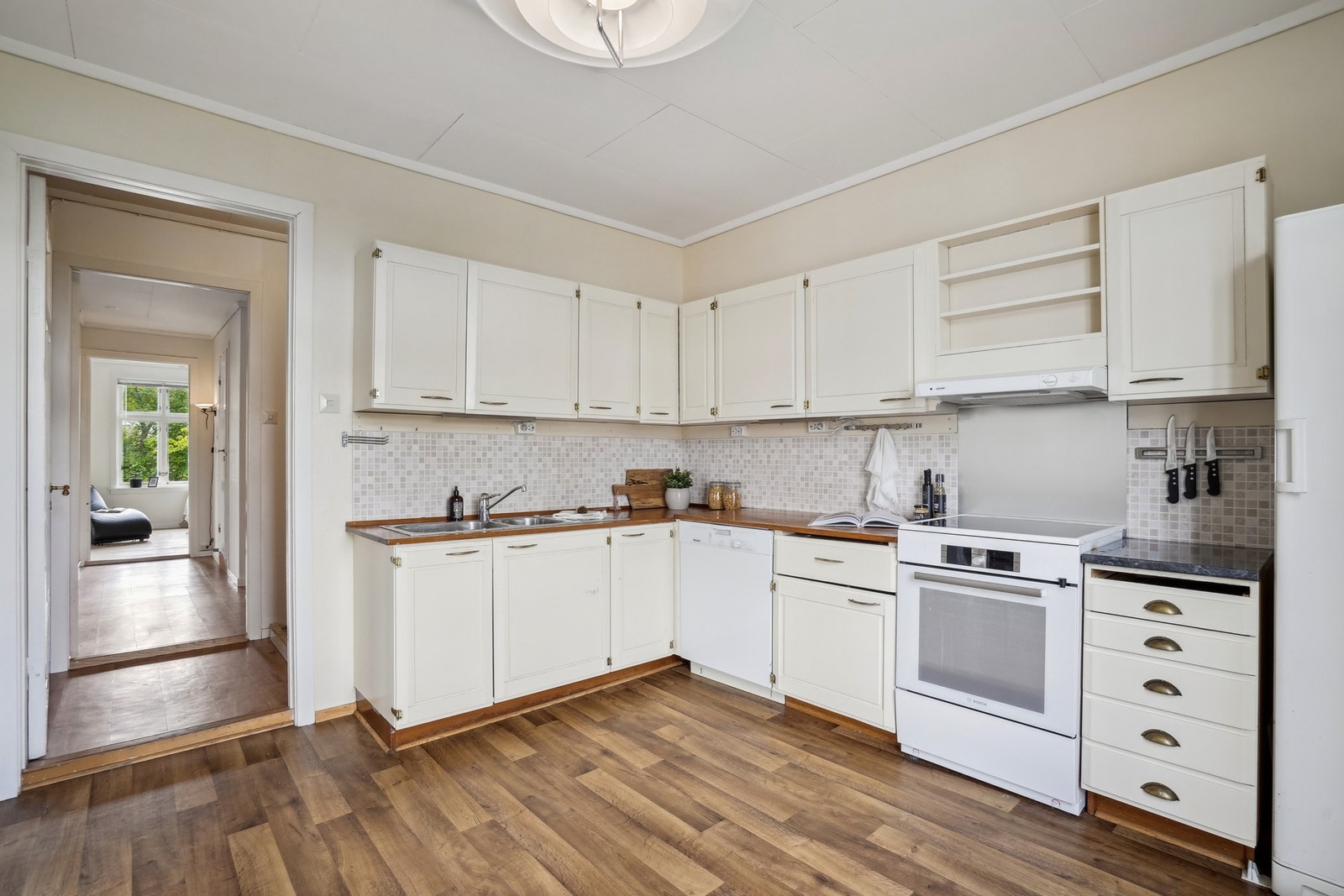 Kjøkkeninnredning med profilerte fronter og laminat benkeplate. Kjøkkenventilator med avtrekk ut. Galleribilde