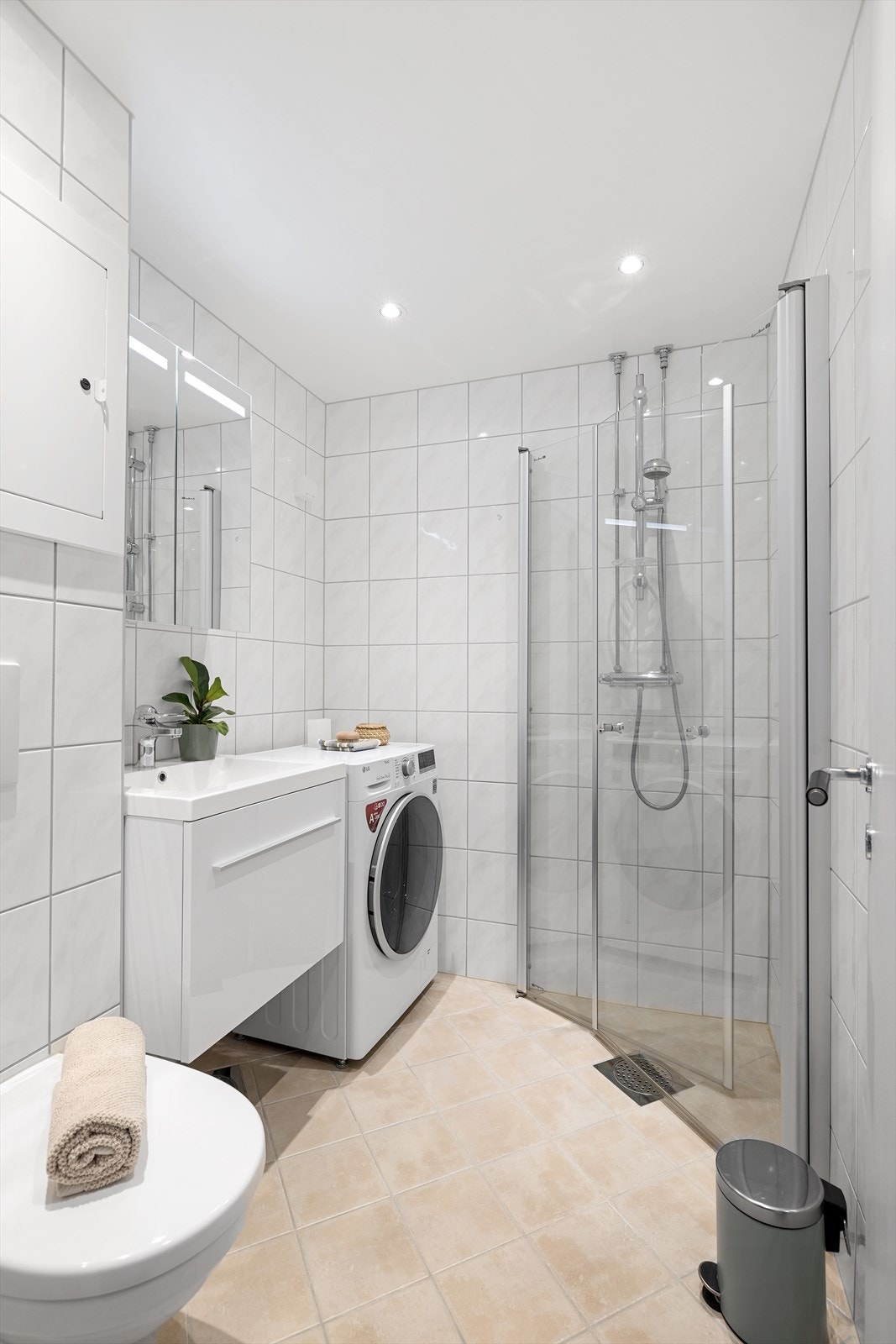 Badet er lyst og tidløst med downlights i himling og elektriske varmekabler i gulv. Det er opplegg for vaskemaskin. Galleribilde