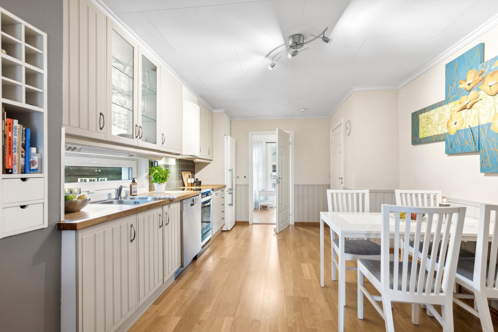 Kjøkkeninnredning med profilerte fronter, overskap med belysning under og ventilator med ventilasjonsanlegg tilkoblet avtrekkskanal. Galleribilde