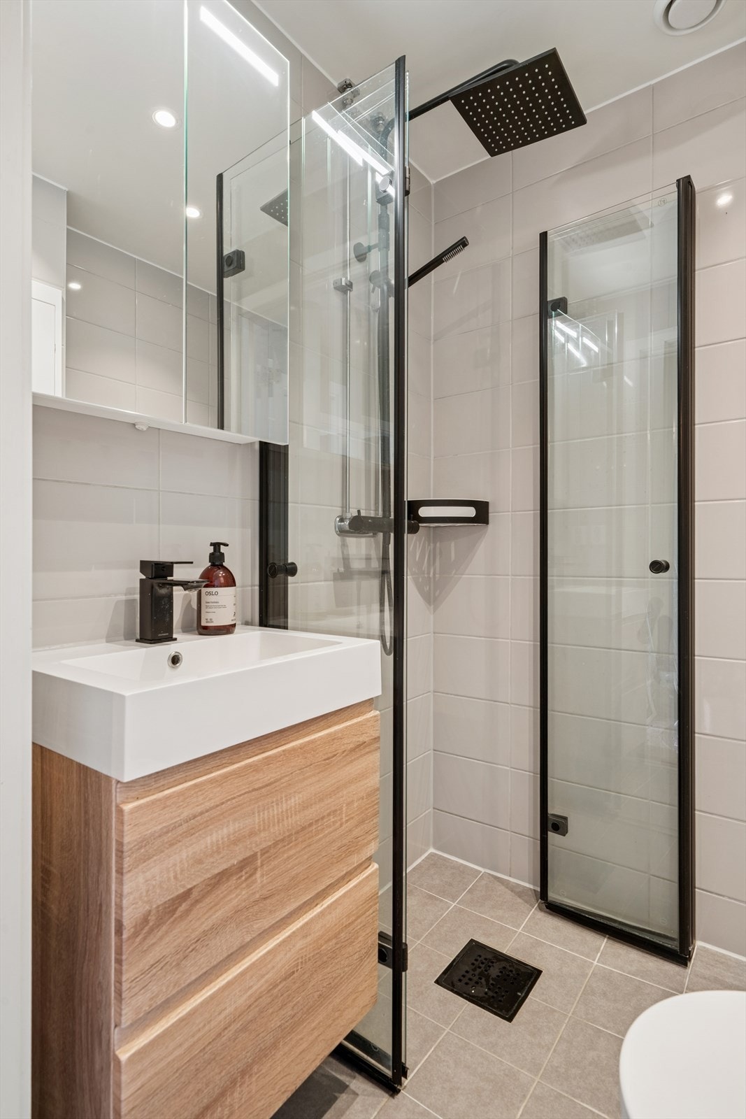 Baderomsinnredning med heldekkende servant, speilskap med belysning og opplegg for vaskemaskin. Galleribilde