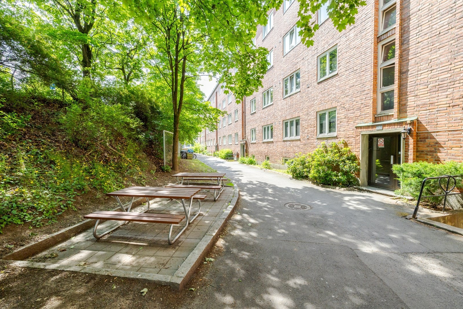 Baksiden av bygget er velholdt med trær og sittegrupper. Galleribilde