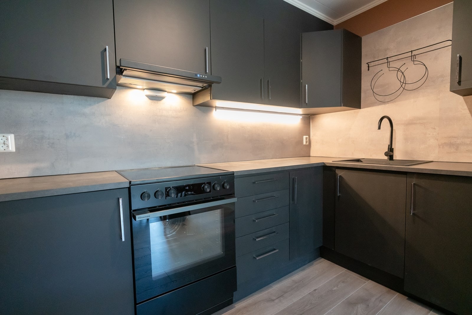 Stilfullt kjøkken med mørke glatte frontar og benkeplate i laminat. Galleribilde