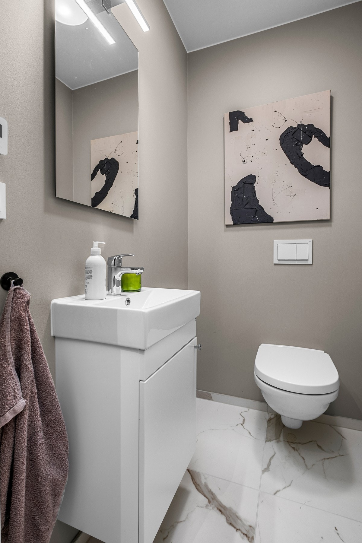 Vegghengt toalett med servant ligger vegg i vegg med baderommet. Galleribilde