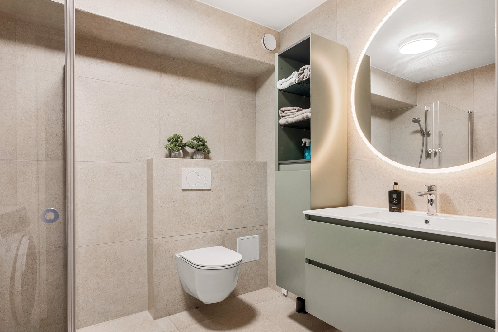 Badet fremstår delikat og tidløst med flislagte overflater, varmekabler og godt med skap-, skuffe- og hylleplass. Galleribilde